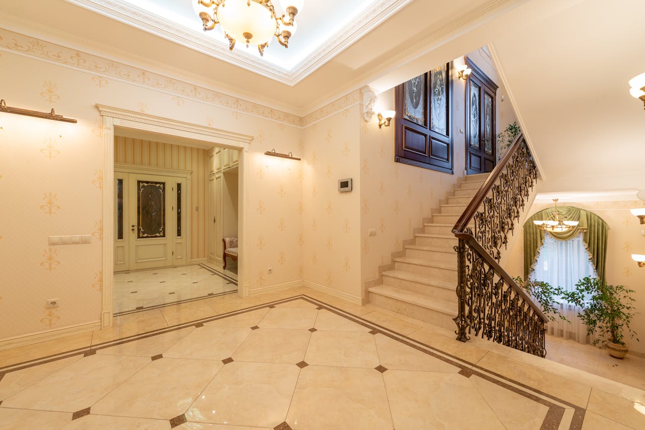 A spacious, well-lit interior featuring a grand staircase and elegant chandelier. Perfect for luxury interior design inspiration.