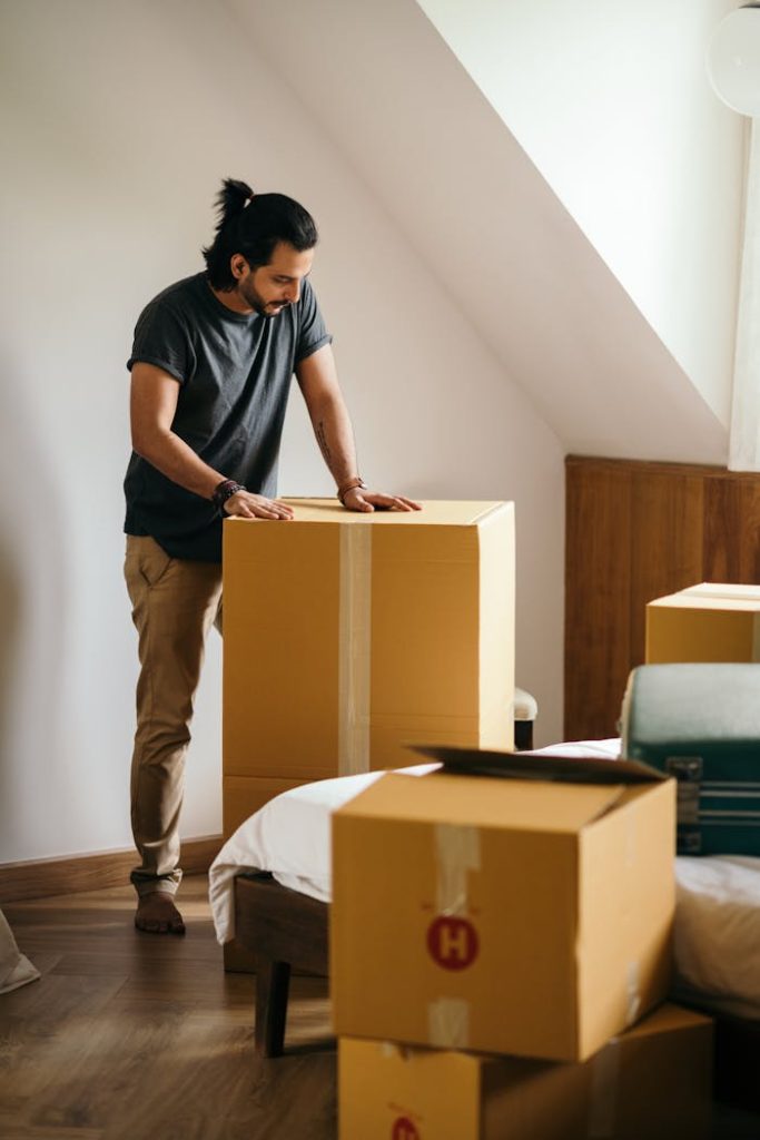 A young man packing cardboard boxes in a modern apartment, preparing for relocation.